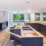 A large kitchen in the middle of a home remodeling project with coverings on the floor and no kitchen countertops yet.