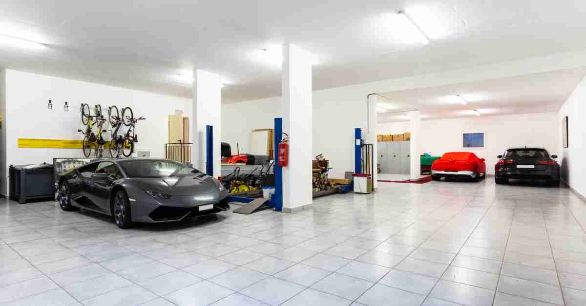 Three cars parked in a tiled garage with white walls, a four-post auto lift, hanging bikes, and storage cabinets.