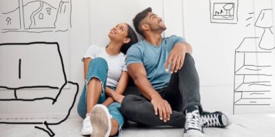A young couple sitting on the floor with sketches of possible home customizations around them thinking about improvements.