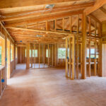 The Pros and Cons of Building a Custom Home A custom home is in the beginning stages. There is wood, wiring, and planks, all exposed due to the lack of drywall.