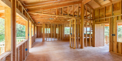 A custom home is in the beginning stages. There is wood, wiring, and planks, all exposed due to the lack of drywall.