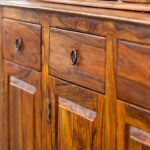 How To Properly Care for Antique Furniture An antique wooden stand with three cabinets beneath three rectangular drawers. It features dark metal hinges and handles.