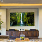 How To Set Up Your Home Entertainment Center A high-end room with a large flat-screen TV and a speaker system. There are couches and pillows in the room.