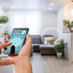 A hand holding a smartphone about to press a lock button in their home's living room. The phone reads "smart home".