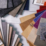 An assortment of colorful laminate and carpet flooring samples displayed across a gray wooden floor.